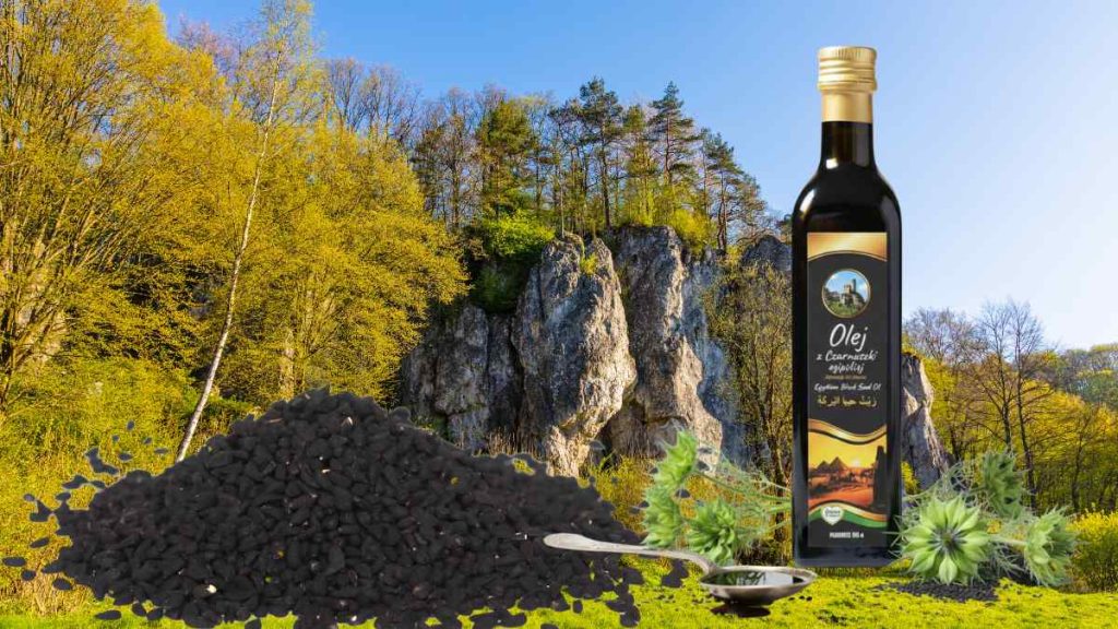 Butelka świeżo tłoczonego na zimno oleju z czarnuszki z Olejów z Jury, obok rozsypane nasiona czarnuszki.